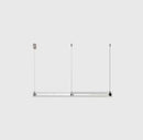 A modern, sleek linear glass pendant light with stainless steel accents, suspended over a counter, dispersing a warm glow.