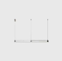 A modern, sleek linear glass pendant light with stainless steel accents, suspended over a counter, dispersing a warm glow.