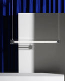 A modern, sleek linear glass pendant light with stainless steel accents, suspended over a counter, dispersing a warm glow.